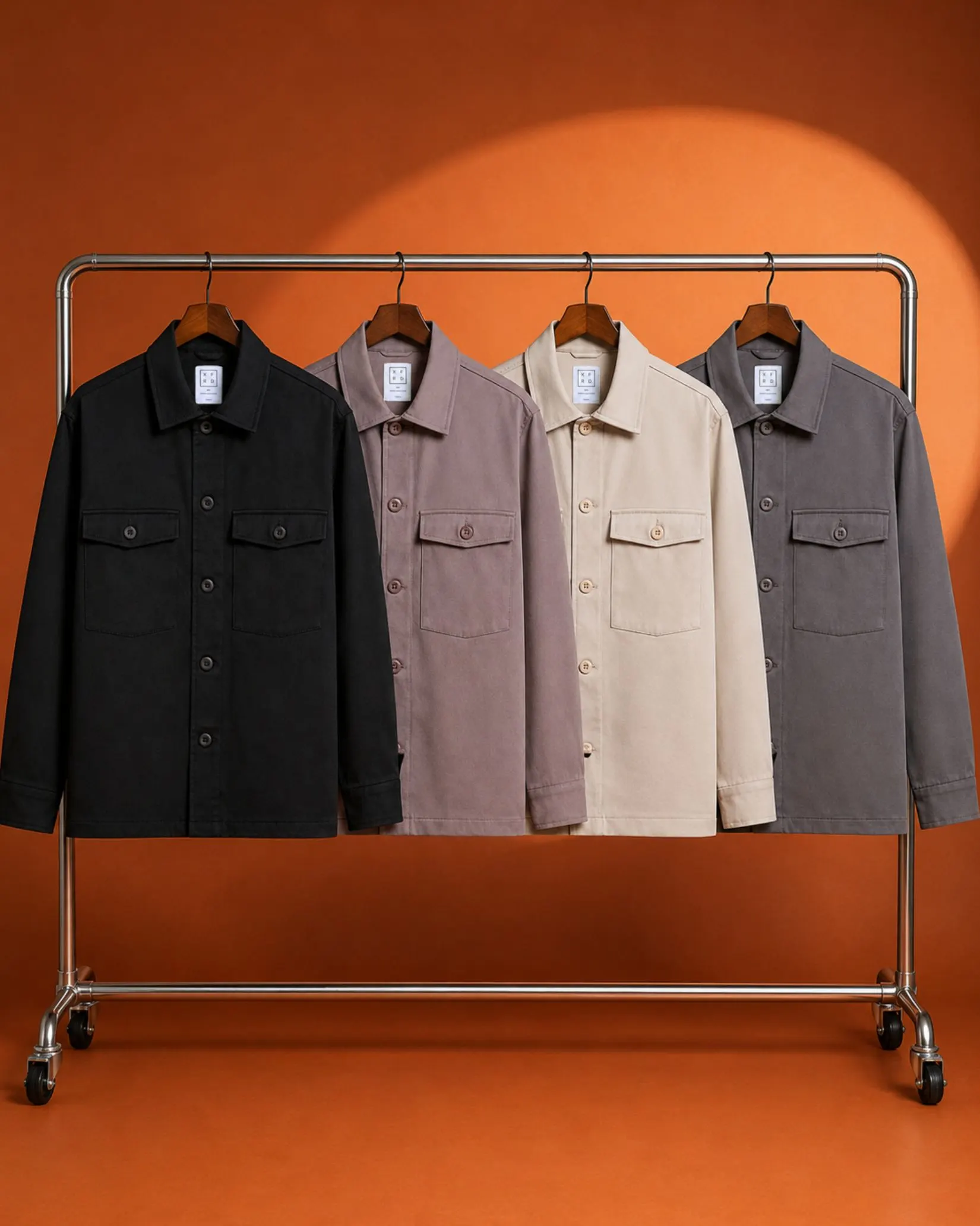 Four Mason Utility Jackets on a clothing rack against an orange wall.