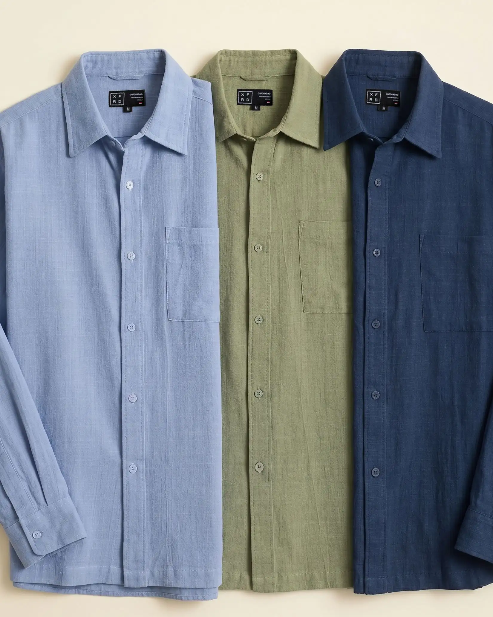 Rextured shirts in light blue, green and navy arranged on a cream background.